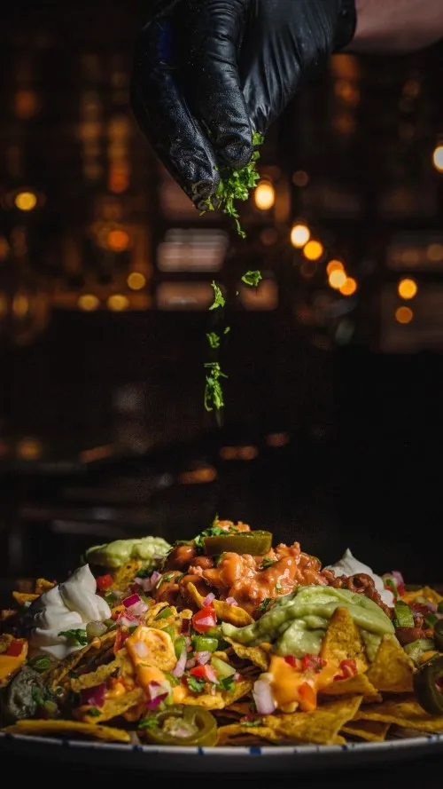 Imagen de unos nachos con queso, guacamole, jalapeños, pico de gallo...