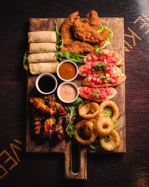 Imagen de una paleta de una paleta de tiras de pollo, pan con tomate, rollitos...